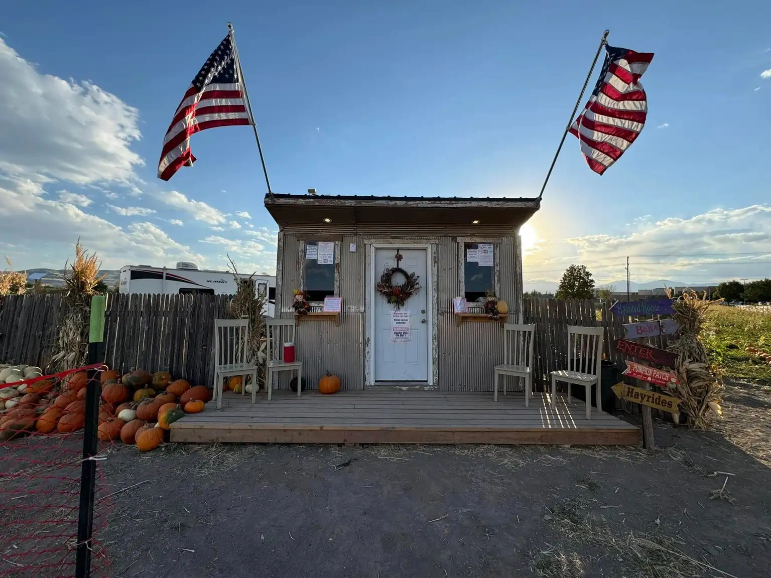 The ticket shed at the patch, flags either side of the door and pumpkins stacked along the deck