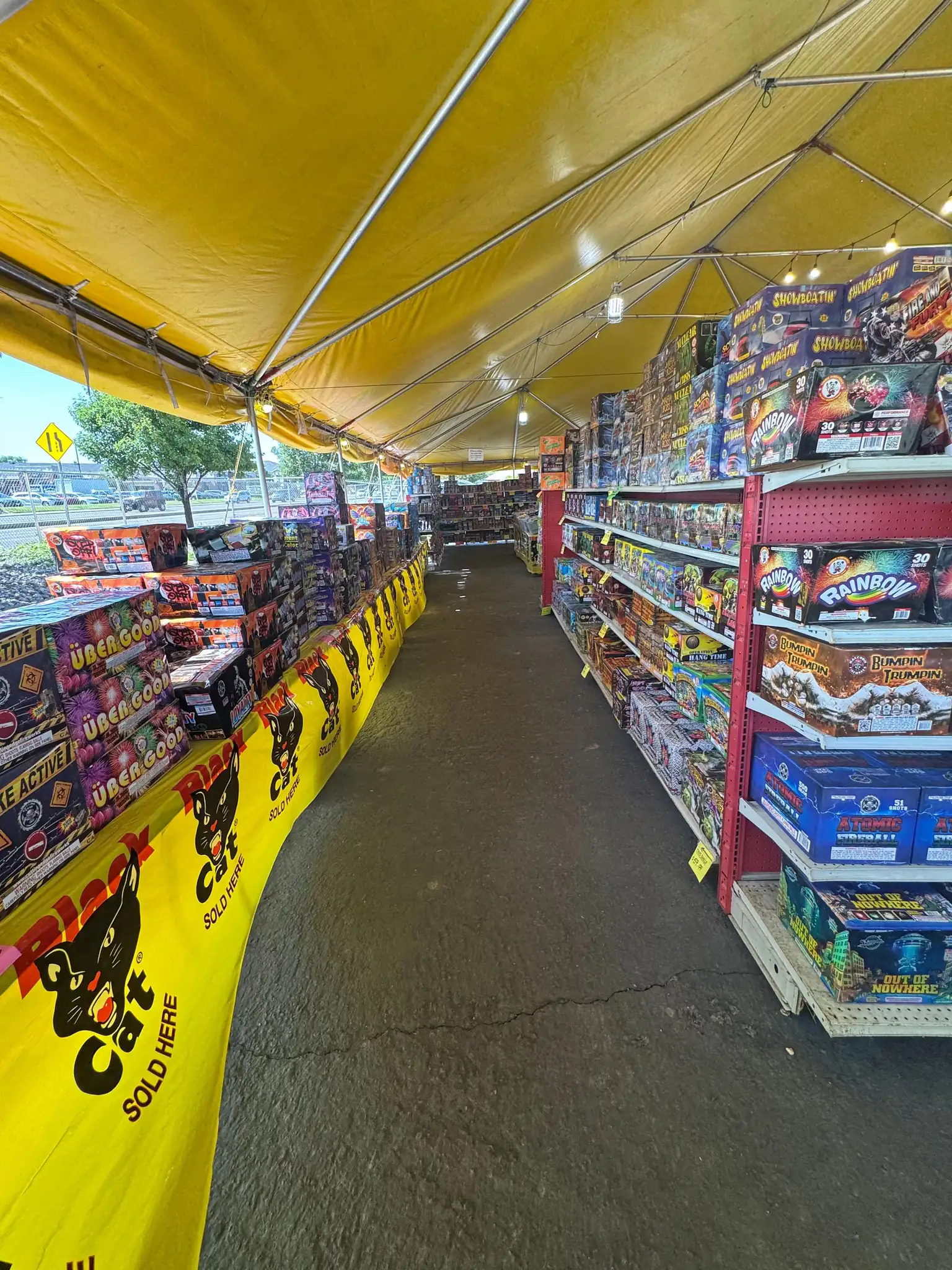 Looking down the aisle under the yellow tent canopy, shelves stacked high on both sides